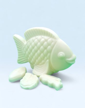 Poisson en chocolat blanc avec écailles moulées, présenté de profil sur fond bleu clair