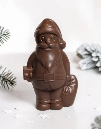 pere noel en chocolat au lait de la maison griess dans un décor de neige et branche de sapin